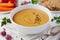 Vegetarian vegetable cream soup with eggplant and carrots in white bowl on wooden table