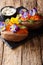 Vegetarian whole baked sweet potato decorated with edible flowers is served with sauce on the board. vertical