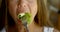 Vegetarian woman is putting leaf of lettuce in her mouth by fork and chewing, close-up view