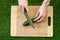 Vegetarians and cooking on the nature of the theme: human hand holding a knife and cucumber on a cutting board and a background of