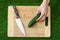 Vegetarians and cooking on the nature of the theme: human hand holding a knife and cucumber on a cutting board and a background of