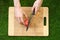 Vegetarians and cooking on the nature of the theme: human hand holding a knife and tomato cutting board on a background of green g