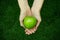 Vegetarians and fresh fruit and vegetables on the nature of the theme: human hand holding a green apple on a background of green g