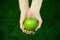 Vegetarians and fresh fruit and vegetables on the nature of the theme: human hand holding a green apple on a background of green g