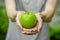 Vegetarians and fresh fruit and vegetables on the nature of the theme: human hand holding a green apple on a background of green g