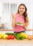 Vegeterian woman standing at table in kitchen and eating vegetable salad