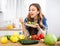 Vegeterian woman standing at table in kitchen and eating vegetable salad