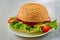 Veggie burger with salad, onion rings, cheese and cherry tomatoes on the gray concrete table. Classic american vegetarian burger