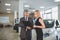 Vehicle dealer and young woman in auto showroom.