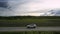 Vehicle drives along old asphalt road under pictorial clouds