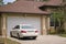 Vehicle parked in front of wide garage double door on paved driveway of typical contemporary american home