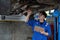 Vehicle service maintenance asian man checking under car condition in garage. Automotive mechanic maintenance checklist