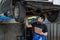 Vehicle service maintenance asian man checking under car condition in garage. Automotive mechanic maintenance checklist