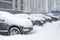 Vehicles covered with snow in the winter blizzard in the parking lot.