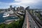 Vehicles cruise along Cahill Highway that projects straight ahead into distance and city skyline with Sydney Harbor