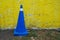 Vehicular control cone in royal blue color against a yellow wall