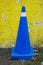 Vehicular control cone in royal blue color against a yellow wall