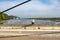 Vehicular road in poor condition on Lanaye cable-stayed bridge, woman hiker standingert canal, two boats sailing, trees,