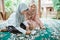 veiled asian mother and daughter making eid mubarak greeting cards