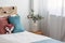 Velvet pastel pink and turquoise pillows and toy fox on single wooden bed with white bedding and blanket