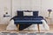Velvet petrol blue bench in front of comfortable big bed with cozy bedding