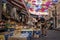 Vendor arranging fruits at stall in market under colorful umbrellas in town