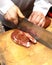 A Vendor slices bacon to his client.