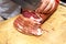 A Vendor slices bacon to his client.