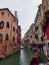 Venetian canal with boats, ancient low-rise houses, cafes and shops