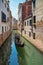 Venetian gondola sailing along narrow canals, popular tourist attraction, Venice, Italy