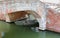 Venetian-style brick bridge with a boat underneath in a navigable canal