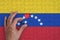 Venezuela flag is depicted on a puzzle, which the man`s hand completes to fold