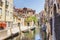 Venice as it is: canal, gondolas, bright buildings and tourists at noon time.