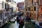 Venice on a beautiful day with small narrow canals and boats and gondolas floating under bridges.