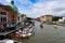 Venice on a beautiful day with small narrow canals and boats and gondolas floating under bridges.