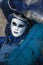 A Venice Carnival character dressed in a colourful blue costume with feathers and Venice mask in February Venice Italy