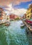 Venice cityscape at sunset time, Italy. Cannaregio canal street view with two beautiful bridges, lot of boats and restaurants.