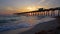 Venice fishing pier in Florida at sunset. Evening seascape with surf waves crashing on sandy beach covered with