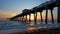 Venice fishing pier in Florida at sunset. Evening seascape with surf waves crashing on sandy beach covered with