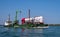 Venice, Italy - 07 May 2018: Self-propelled barge carrying an excavator and a tanker truck across the Venetian lagoon