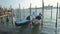 Venice, Italy docked empty gondolas on wooden mooring piles.