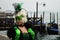 VENICE, ITALY - Feb 09, 2016: A lady in a beautiful green costume during the Carnival of Venice, with gondolas in the background