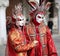 Venice, Italy - February 5, 2018: woman and man with red and golden dress near the Ducal Palace