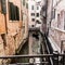 Venice, Italy - March 11, 2012: Typical Gondola with gondolier rowing along a narrow canal in Venice