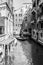 Venice, Italy - March 11, 2012: Typical Gondola with gondolier rowing along a narrow canal in Venice, black and white image