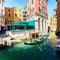 Venice, Italy - March 11, 2012: Typical venetian gondola with gondolier rowing along a narrow canal in Venice