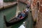 Venice, Italy - October 13, 2017: Tourists sail on a gondola on a narrow canal. The gondola is richly decorated with red