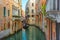 Venice, Italy. Venetian gondolier floating on gondola with tourists through green canal waters of Venice