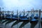 Venice lagoon early spring morning at dawn and blue gondolas anchored at the seafront.