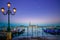 Venice, street lamp and gondolas or gondole on sunset and church on background. Italy